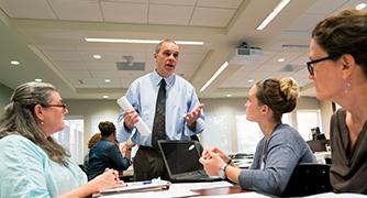 An image of adult students at a desk. 