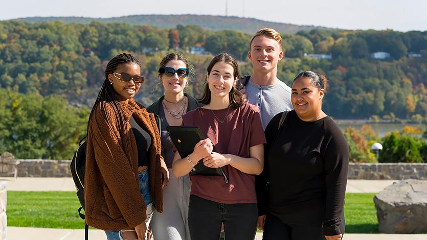 Image of students standing and smiling on campus. 